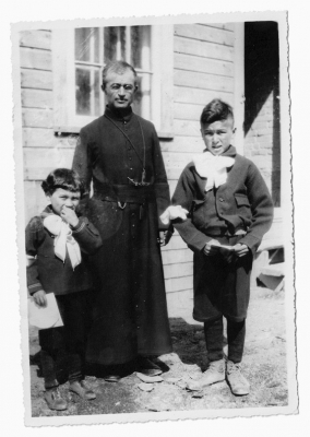 A Catholic priest with a Cree boy and girl
