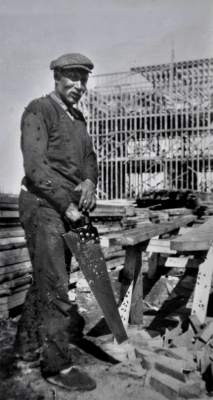 Worker with hand saw cutting boards