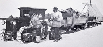Men refuelling a tractor sled train on frozen land
